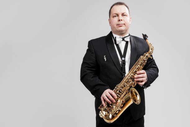 istock Man with Saxophone in Suite Posing Against White Background. Horizontal Image Orientation 1151844207