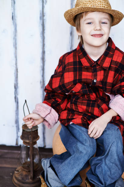 istock Adorable little boy in big farm clothes 1151853745