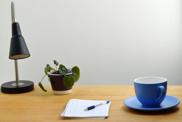 istock Study desk with notepad, coffee, lamp and green plant on the table 1151856126