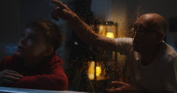 ragazzo che guarda la tempesta con il nonno - lightning house storm rain foto e immagini stock