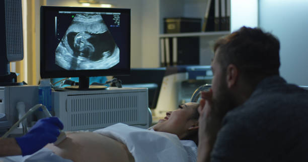 Couple watching ultrasound image of future child Medium close-up of a young couple watching ultrasound image of future child during ultrasound scan pregnant ultrasound stock pictures, royalty-free photos & images