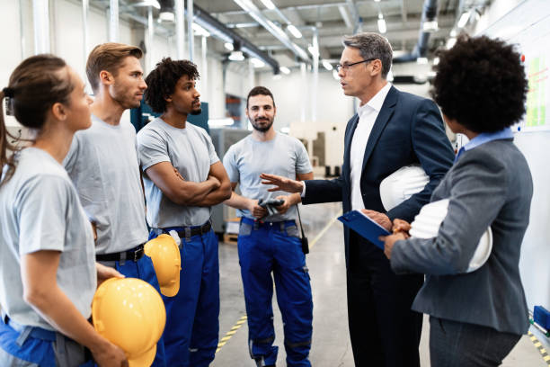 istock Corporate manager talking to group of workers while visiting a factory. 1151862165