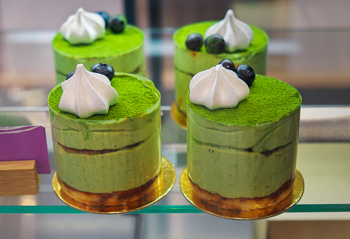 Cheesecakes with green tea matcha, close-up, on a showcase in a cafe