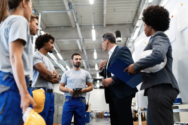 istock Male engineer communicating with group of workers in a factory. 1151863262