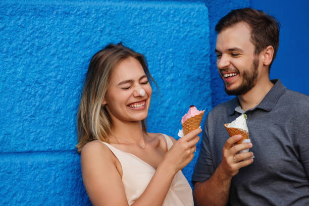 istock Romantic couple eating ice cream and having fun on blue wall background 1151867616