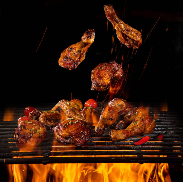 istock Chicken legs and wings on the grill with flames 1151868921