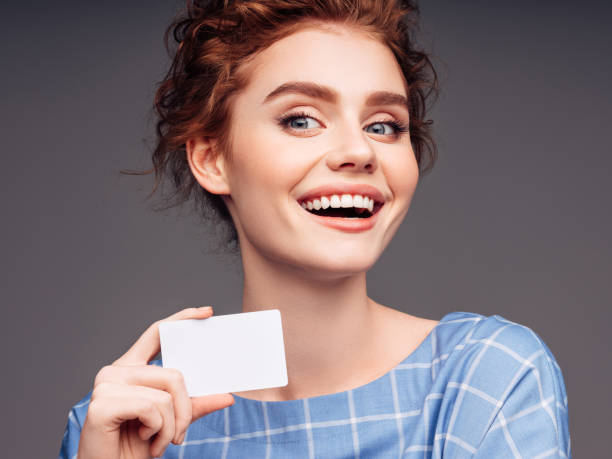 jovencita sosteniendo una tarjeta de visita - smiling business card horizontal women fotografías e imágenes de stock