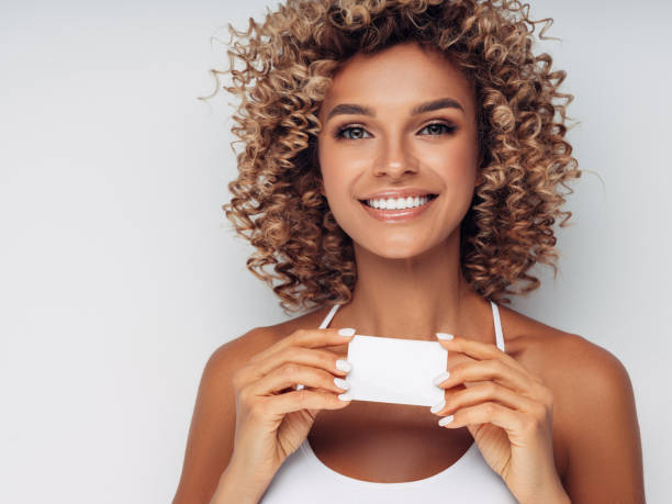 istock Smiling woman with afro curls holding blank card 1151870254