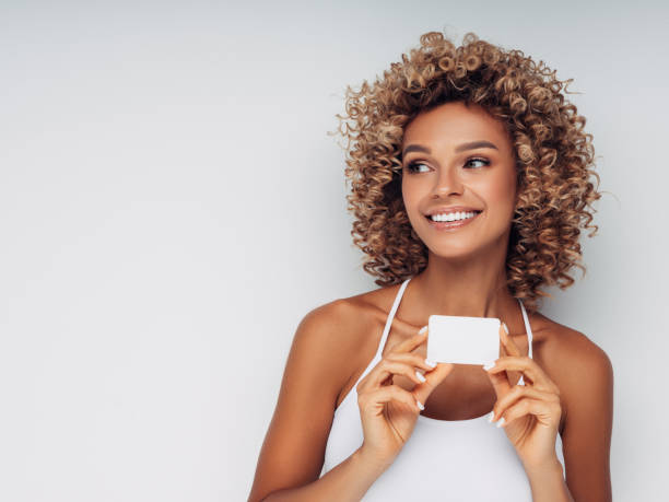 istock Smiling woman with afro curls holding blank card 1151870804