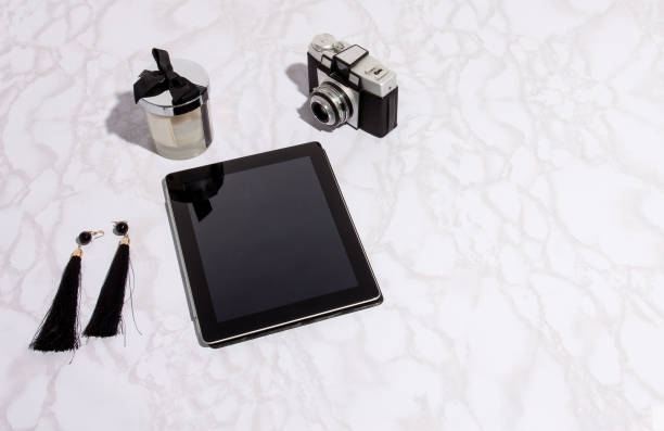 istock Flat lay over marble background. Black tablet near long earrings 1151872455