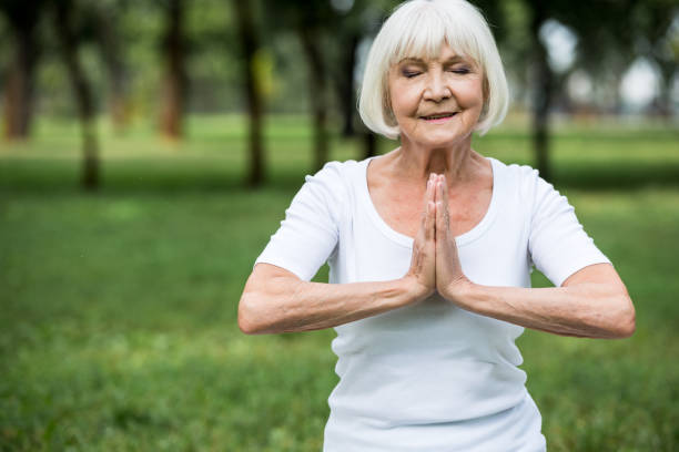 istock senior woman in meditation sukhasana pose with folded hands 1151874162