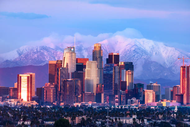 Downtown Los Angeles skyline with snow capped mountains behind at sunset Downtown Los Angeles skyline with snow capped mountains behind at sunset los angeles county stock pictures, royalty-free photos & images