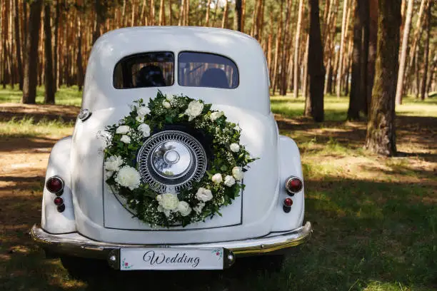 Wedding car with a decoration in the form of a wreath and the word "Wedding"