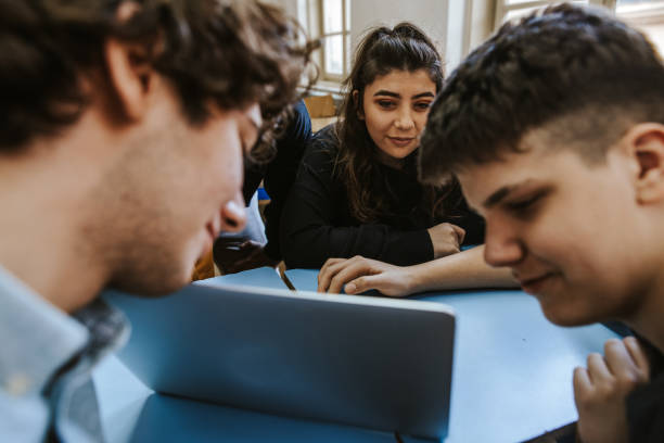 istock Group of teenagers talking and smiling while they are using laptop 1151879014
