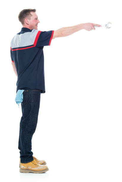 istock Young handsome male mechanic standing on white background - pointing 1151880096