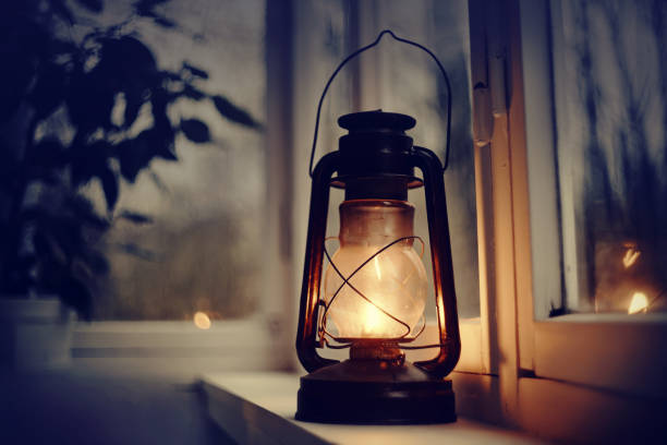 vintage kerosene lamp stands on a white windowsill - oil lantern imagens e fotografias de stock