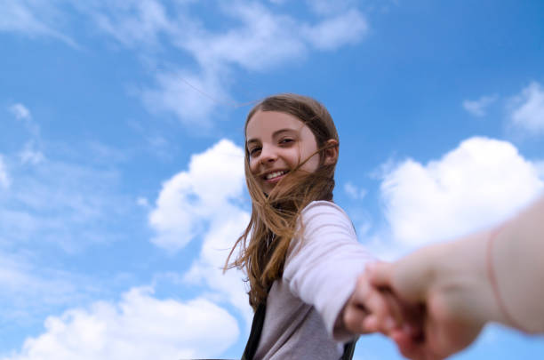 pequeña niña bonita tomando la mano madre en el fondo del cielo azul - moviendo hacia abajo fotografías e imágenes de stock