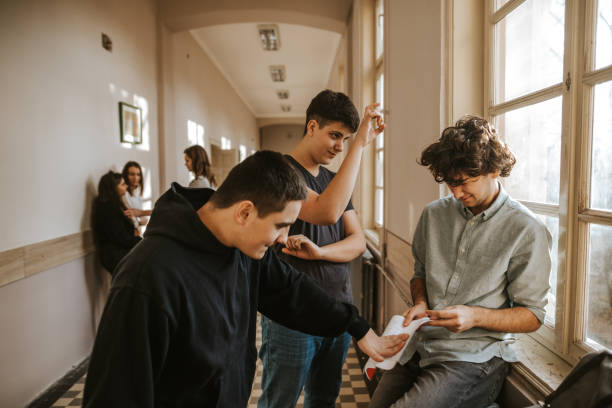 Boys bullying classmate in the school corridor while girls watching Boys bullying classmate in the school corridor while girls watching teasing stock pictures, royalty-free photos & images