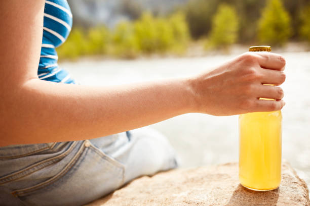 istock Young woman drinking juice by the river 1151893060