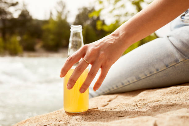 istock Young woman drinking juice by the river 1151893065