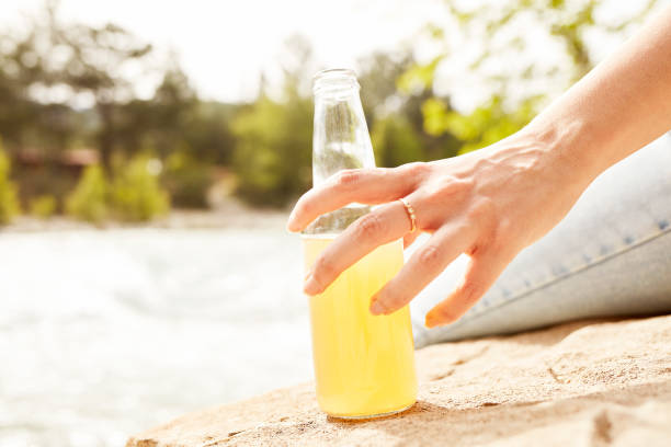 istock Young woman drinking juice by the river 1151893120