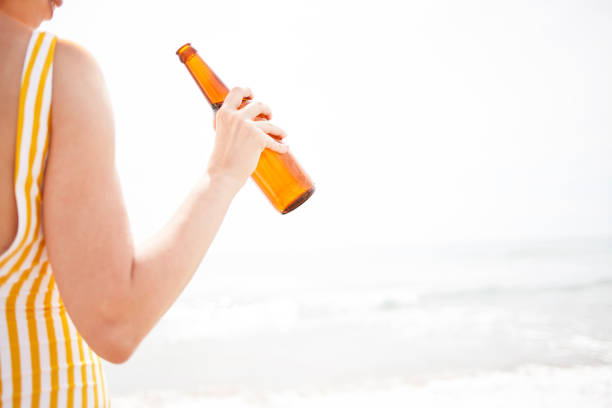 Woman drinking beer on the beach