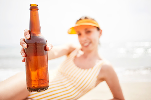 Woman drinking beer on the beach