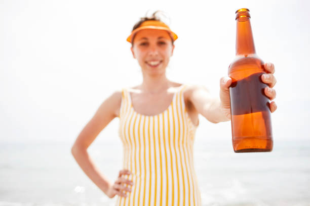 Woman drinking beer on the beach