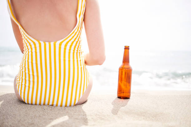 Sand of beach with chairs, a black celular phone and a plastic cup.