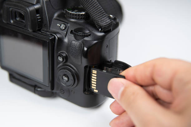 istock Photographer hand holding SD memory card insert DSLR camera 1151903144