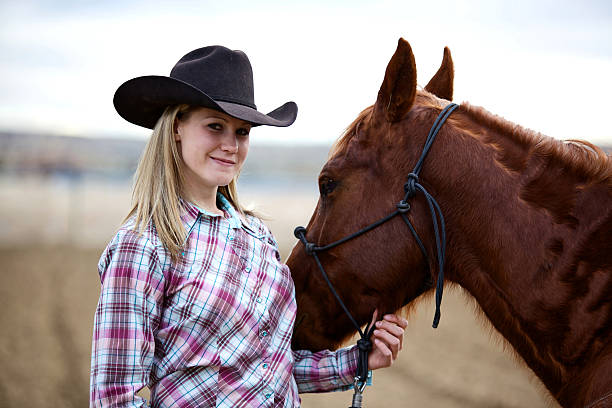 An elegant woman leads a horse by the bridle across the field. Picturesque nature on a summer day