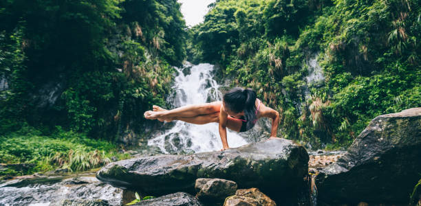 junge frau praktiziert yoga in der nähe von wasserfall im wald - waterfall water nature zen like stock-fotos und bilder