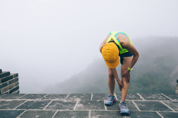 donna trail runner tenere le gambe sportive ferite in cima alla montagna - stinco gamba umana foto e immagini stock