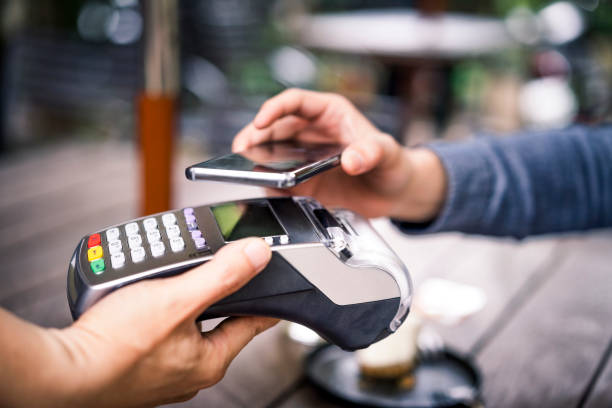 Customer paying using mobile payment to cafe owner Close-up of customer paying for his coffee through mobile payment. Owner is holding credit card reader. They are in cafe. mobile payment photos stock pictures, royalty-free photos & images