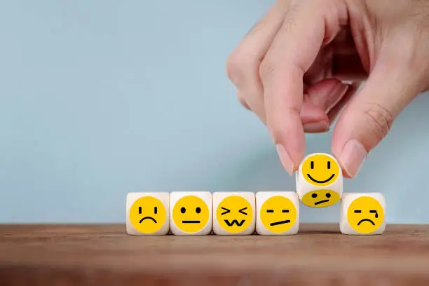Hand Changing with smile emoticon icons  face on Wooden Cube , hand flipping unhappy turning to happy symbol