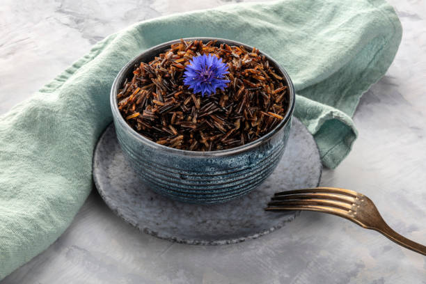 istock Wild black rice with an edible flower, a blue cornflower, with a fork and copy space 1151928483
