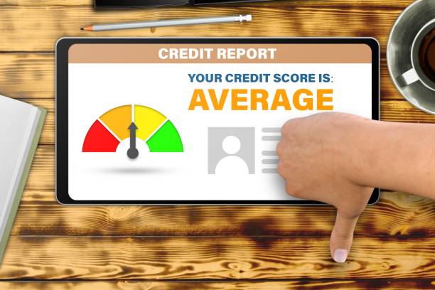istock hand with tablet pc shows dislike, thumb down   on wooden table background - average credit score technology concept 1151930252