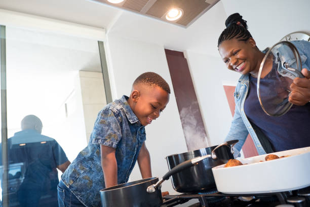 istock Smiling mother looking at boy while preparing food 1151931431
