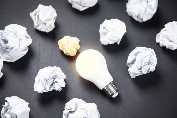 istock Light bulb and crumpled papers in the black background. Idea 1151934005