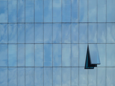 Modern building with reflections from the sky and one opened window