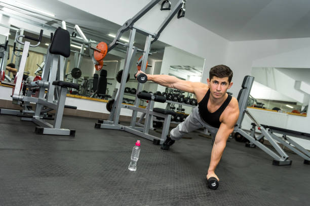 istock Athletic man in gym working with dumbbells 1151944534