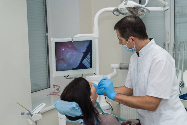 dentista que verific os dentes do paciente com a câmera na estomatologia - medical exam dental hygiene caucasian mask - fotografias e filmes do acervo
