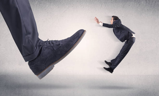 istock Small businessman kicked by big shoe 1151945588