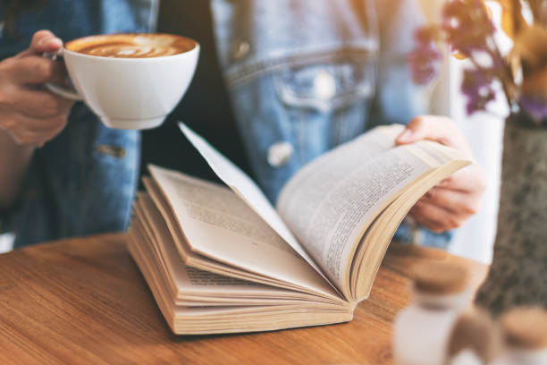 istock a woman holding and reading a vintage novel book while drinking coffee 1151945841
