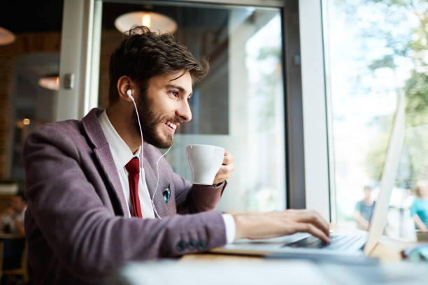 istock Young man at cafe drinking coffee and working on laptop 1151948215