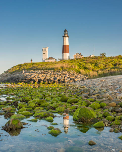 istock Lighthouse beacon sitting on a cliff overlooking the ocean during sunset. 1151950646