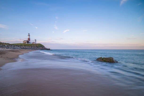 istock Lighthouse beacon sitting on a cliff overlooking the ocean during sunset. 1151950667