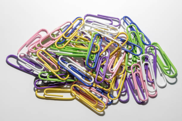 istock Multicolored paper clips in a plastic coating lie on a white background. 1151951015