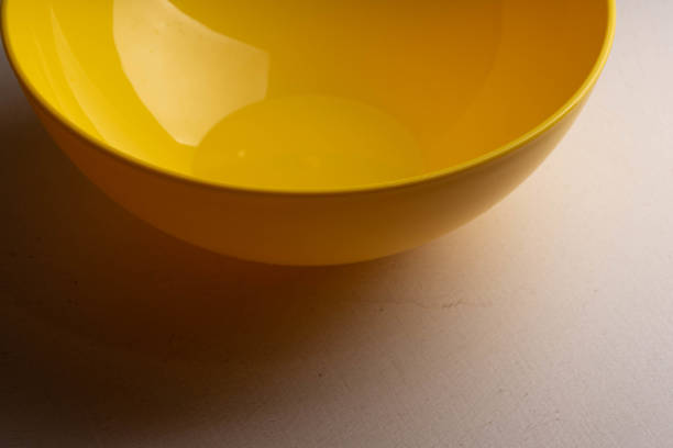 A yellow salad bowl with water drops on the wall is on the table.
