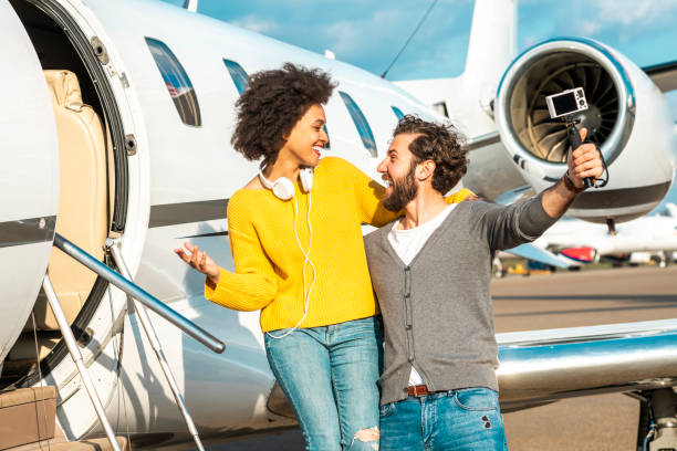 istock Multi-ethnic couple making a vlog video together while hugging each other on the boarding stairs of a private airplane 1151955115